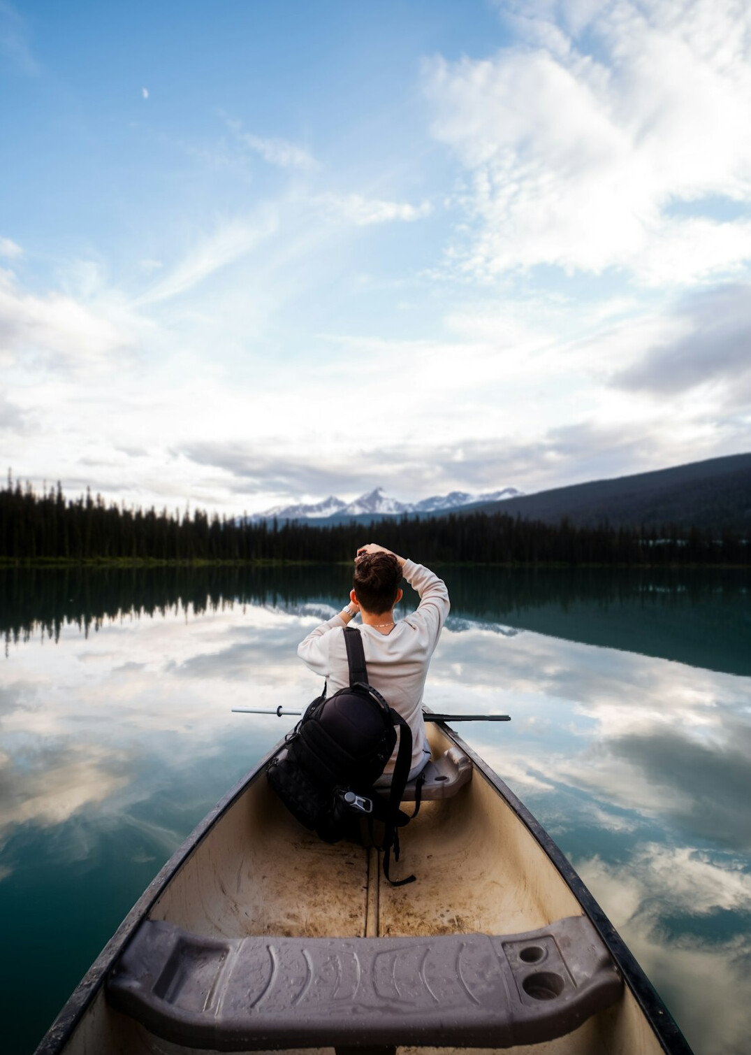 Photographer crouched by a lake in the Canadian Rockies photographing a mountain view